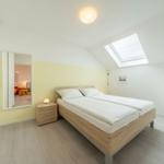 Schlafzimmer mit Dachschräge, Dachfenster und Holzbett. Nebenraum sichtbar.
