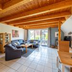 Wohn- und Essbereich mit Holzdecke, Sofa, Esstisch und Blick auf die Terrasse.