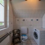 Badezimmer mit Toilette, Waschmaschine und Fenster mit Seetang-Dekoration.