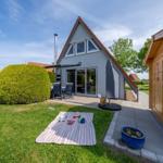 Haus mit Terrasse, Garten und Picknickdecke. Holzschuppen nebenan.