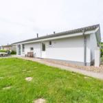 Wohnhaus mit Garten, Terrasse und Grillplatz. Einfahrt und Fenster sichtbar.