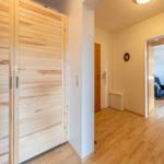 Haus mit Holzschrank, Flur und Blick in Wohnzimmer mit Sofa und Sessel.