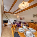 Wohnbereich mit Essplatz, Sofa, TV und Treppe zur oberen Etage.