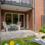 Terrace with table and chairs, garden with lounge chair and childrens toys.