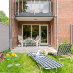 Backyard with lounge chairs, toys, and terrace in front of brick facade.