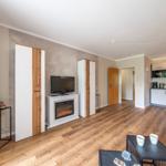 Wohn- und Küchenbereich mit Holzboden, Fernseher und Kamin.