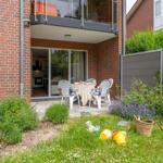 Terrasse mit Tisch und Stühlen, Blick in die Küche, Garten mit Blumen und Spielzeug.