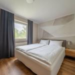 Schlafzimmer mit Doppelbett, Fenster und Holzboden.