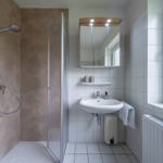 Badezimmer mit Dusche, Waschbecken und Spiegel