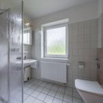 Badezimmer mit Dusche, Waschbecken und Toilette. Fenster mit beschlagener Scheibe.
