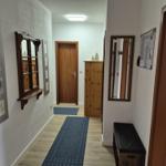 Flur mit Holzboden, blauem Teppich, Spiegel und Garderobe.