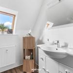 Badezimmer mit Waschbecken, Spiegel, Dachfenster und Holzregal.