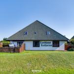 Landhaus Katharina mit grünem Garten und Holztor. Dach mit Dachfenstern.