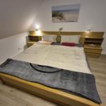 Schlafzimmer mit Holzbett, Nachttischen und Wandbild