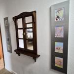Wand mit Holzfenster und Kindergemälden in Rahmen