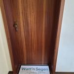Holztür mit Nummer 5 und Willkommensmatte vor Eingang.