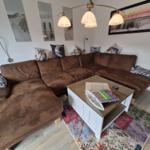 Ein Wohnzimmer mit braunem Sofa, weißem Couchtisch und Wandbildern.
