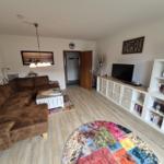 Wohnzimmer mit braunem Sofa, TV-Bereich und Bücherregal.
