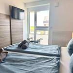 Schlafzimmer mit Doppelbett, TV und Balkon. Handtuchrollen auf dem Bett.