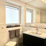 Bathroom with sink, mirror, shower, and window with blinds.