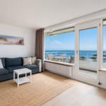 Living room with sofa, rug, and balcony view of the sea.