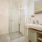Bad mit Dusche, Waschbecken und Toilette. Moderne Einrichtung.