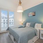 Schlafzimmer mit Bett, Nachttisch, Fernseher und Fenster mit Blick.