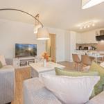 Wohnzimmer mit Sofa, Fernseher und Essbereich mit Tisch und Stühlen.