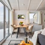 Wohn- und Essbereich mit Tisch, Stühlen und Sofa. Große Glasfront mit Blick auf Schnee.