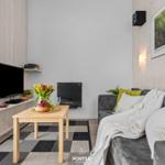 Wohnzimmer mit Sofa, Fernseher, Kamin und Tisch mit Blumen.