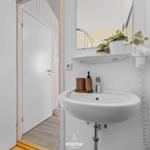 Waschbecken mit Spiegel, Pflanze und Handtuchhalter in einem Badezimmer.