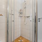 Duschkabine mit Glaswand, Duschbrause und Ablagefläche. WC und Badewanne sind ebenfalls vorhanden.