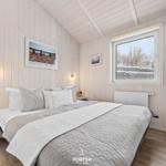 Schlafzimmer mit Bett, Fenster und Holzwandverkleidung.