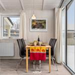 Esszimmer mit Tisch, Stühlen und Blick auf Schnee. Holzwand, Fenster und Glastür.
