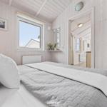 Schlafzimmer mit Bett, Fenster und Holzwandverkleidung. Blick in angrenzenden Raum.