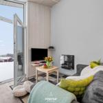 Wohnzimmer mit Sofa, Fernseher und Blick auf verschneiten Balkon.