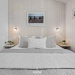 Schlafzimmer mit Bett, Wandbildern und Nachttischen mit Pflanzen.