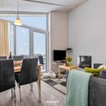 Wohn- und Essbereich mit großem Fenster, Sofa, Fernseher und Kamin.