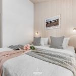 Schlafzimmer mit Bett, Kleiderschrank und Holzwand. Auf dem Bett liegt eine Blume.