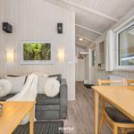 Wohn- und Essbereich mit Sofa, Tisch und Fenster. Holzwände und -boden.