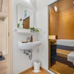 Waschbecken mit Spiegel und Sauna im Hintergrund