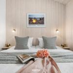 Schlafzimmer mit Holzwand, Bett, Kissen und Bild an der Wand.