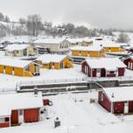 Schneebedeckte Ferienhäuser in bunten Farben auf einer Hanglage.