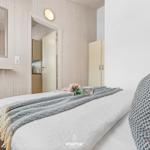 Schlafzimmer mit Bett, Kleiderständer und Spiegel an der Wand