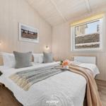 Schlafzimmer mit Holzwand, Bett, Fenster und dekorativen Elementen.
