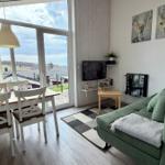 Wohn- und Essbereich mit grünem Sofa, TV und Blick auf die Terrasse.