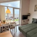 Wohn- und Essbereich mit grünem Sofa, TV und Blick auf die Umgebung.