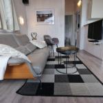 Wohnzimmer mit Sofa, Tisch und Küche im Hintergrund.