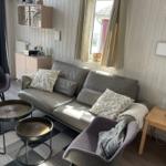 Wohnzimmer mit Sofa, zwei Sesseln und zwei runden Tischen auf gemustertem Teppich.