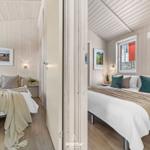 Zwei Schlafzimmer mit Holzwänden, Betten und Fenstern.